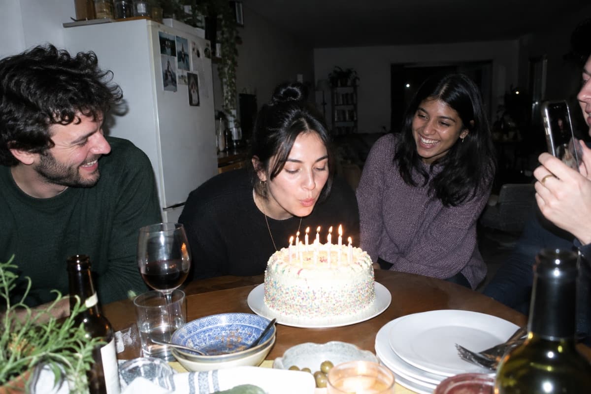 Friends laughing as the birthday candles get blown out, one of them filming